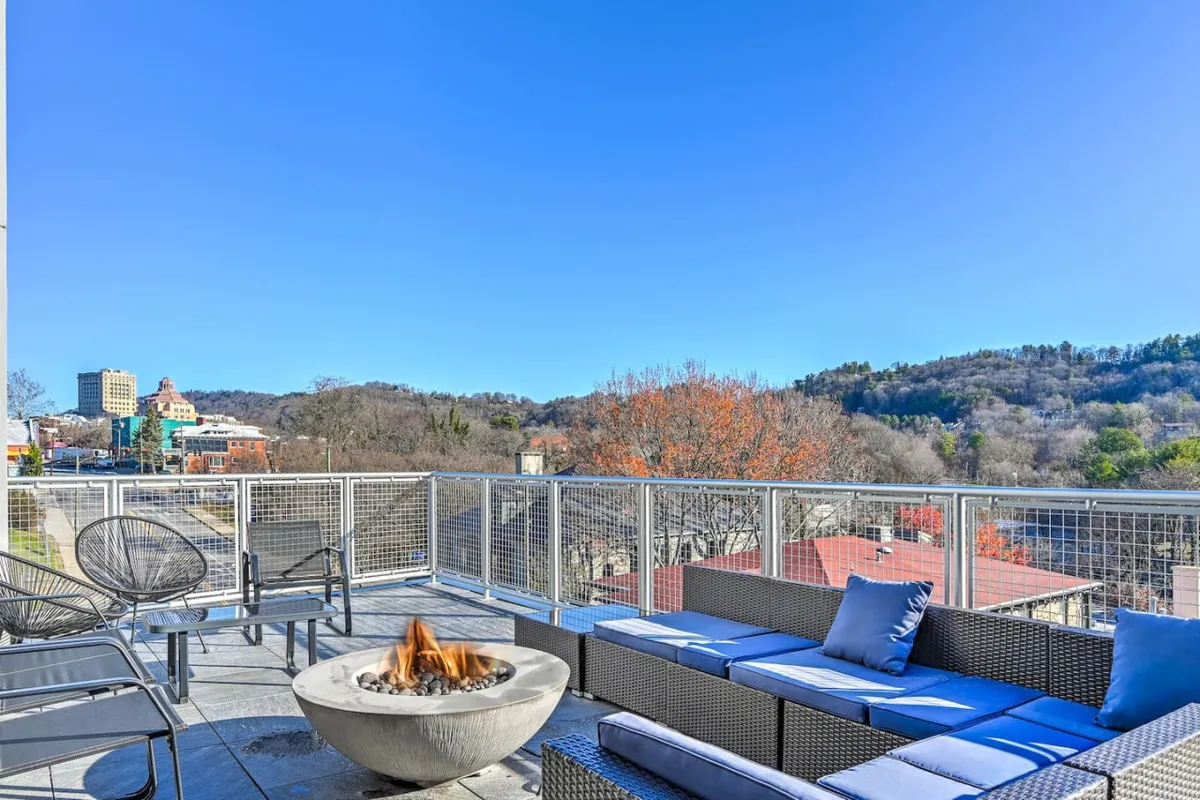 This image captures a cozy outdoor seating area surrounding a fire pit, with expansive mountain views in the background. The space is nestled on a private balcony or patio, ideal for relaxing, enjoying morning coffee, or hosting a small gathering against a serene, scenic backdrop.
