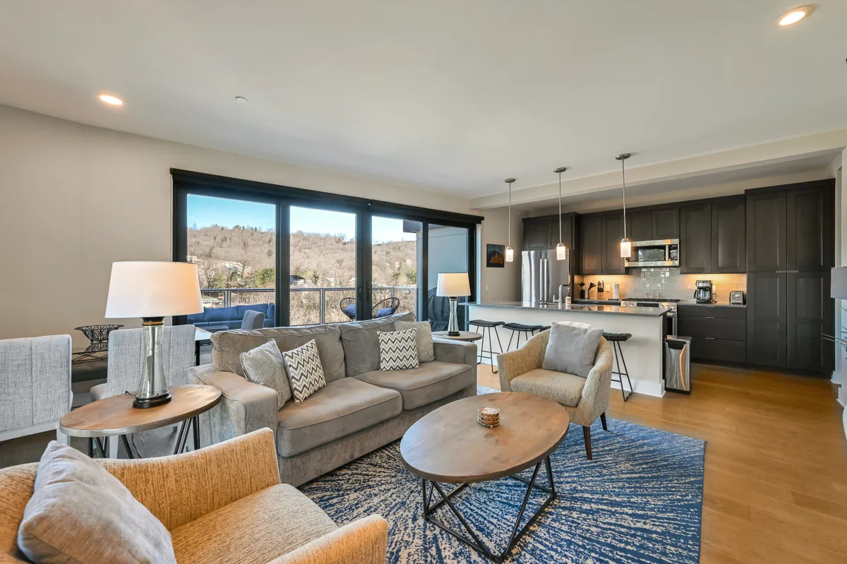 A spacious, light-filled living area with floor-to-ceiling windows that frame breathtaking mountain and city views. Comfortable sofas and a stylish coffee table invite guests to relax, read, or socialize, while natural light enhances the room’s warmth and connection to the outdoors.