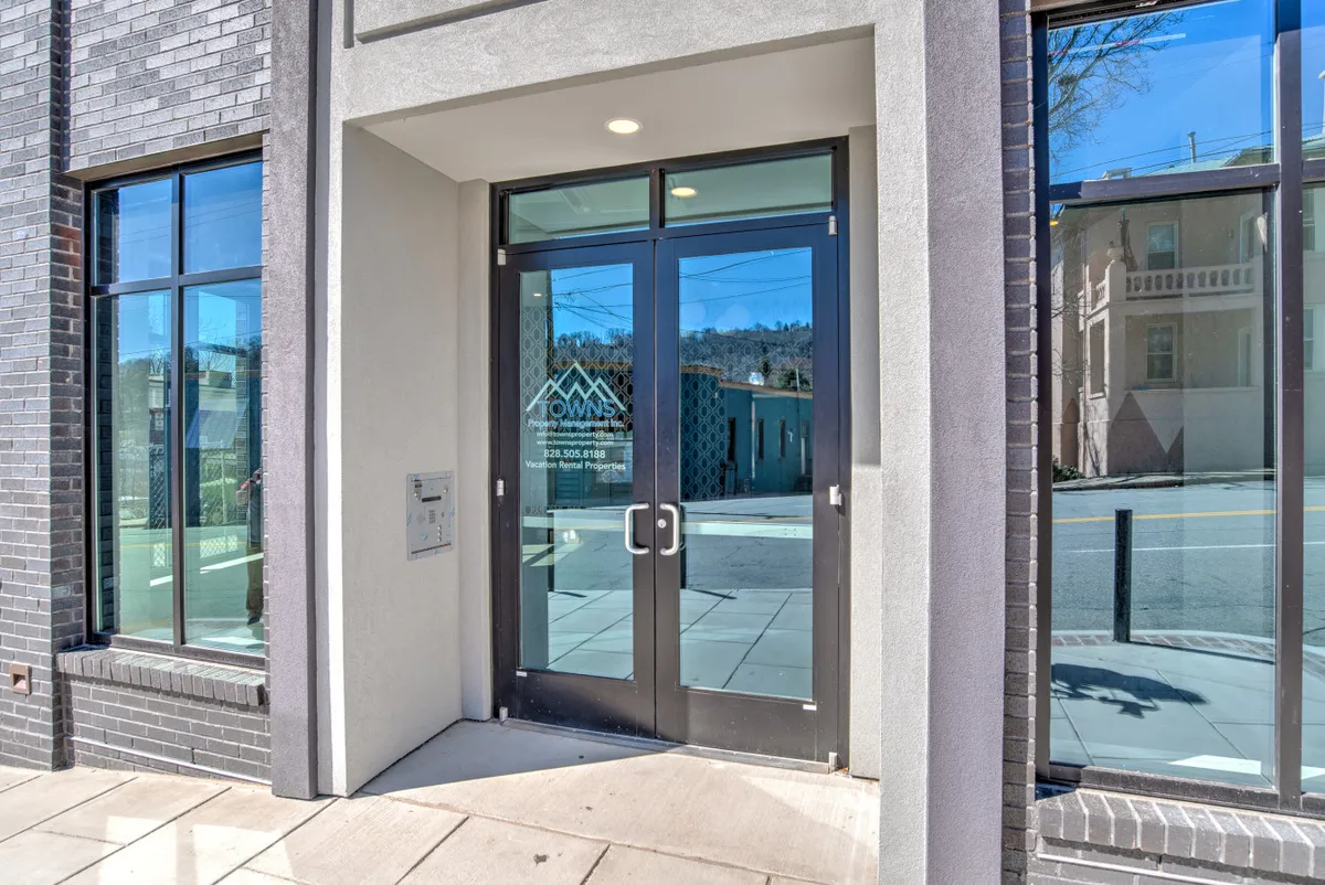The exterior view of the condo building, featuring charming brick walls, large welcoming windows, and prominent entrance doors. The soft lighting creates a warm, inviting ambiance, suggesting a pleasant arrival and the beginning of an urban adventure.