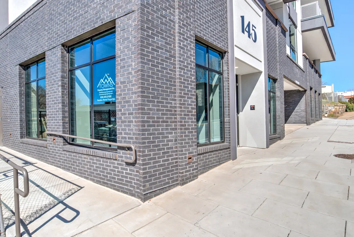 The contemporary exterior of the building with large windows and a clear view of the address number 145. People can be seen walking by, hinting at the vibrant city atmosphere and easy access to nearby attractions.